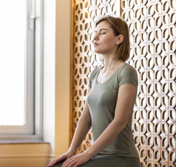 Femme assise en train de faire une séance de sophrologie assise. Elle porte un T-shirt vert.
